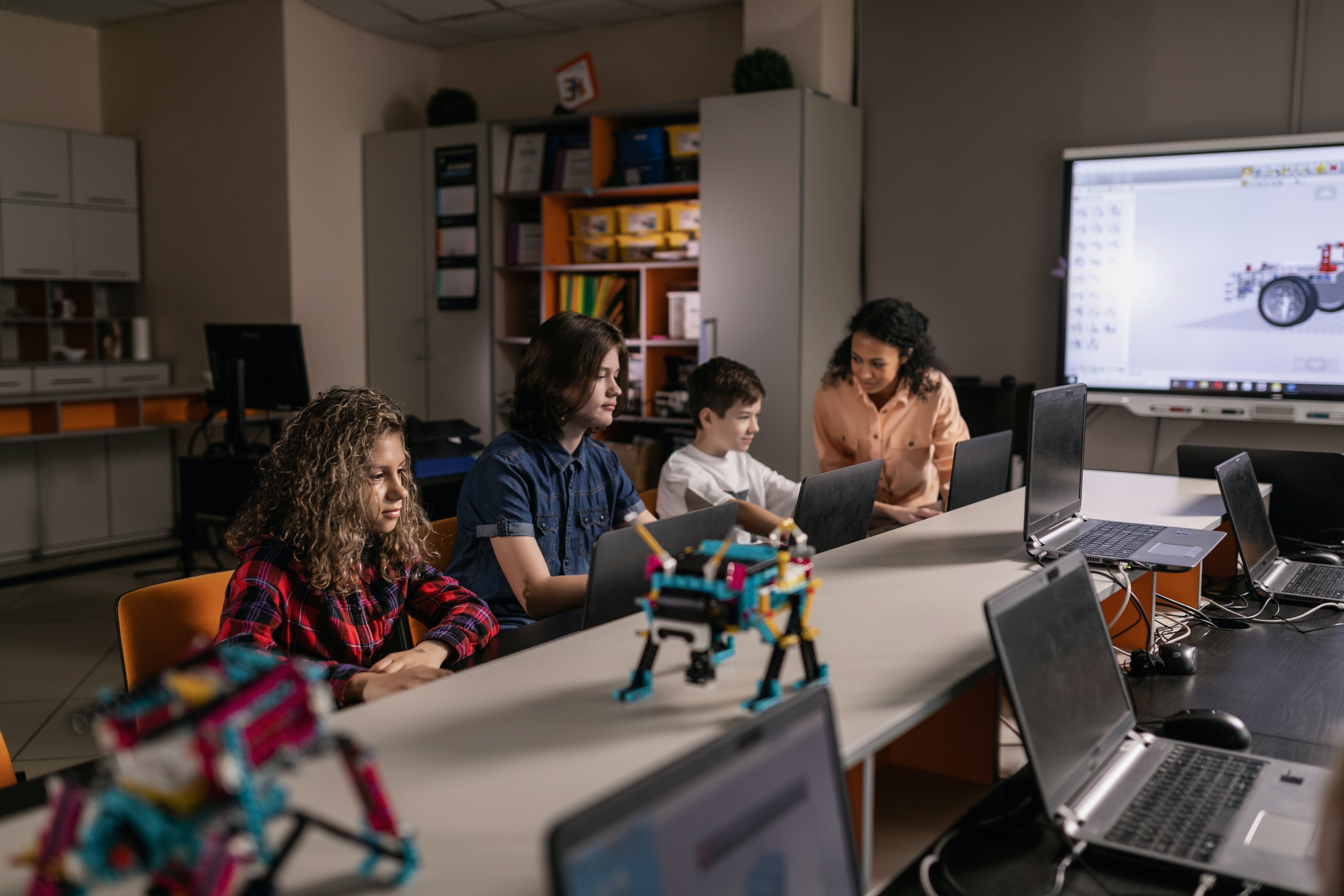 kids learning robotics on laptops with their teacher 